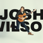 Josh Wilson holding guitar and jumping in mid air in front of text "Josh Wilson".