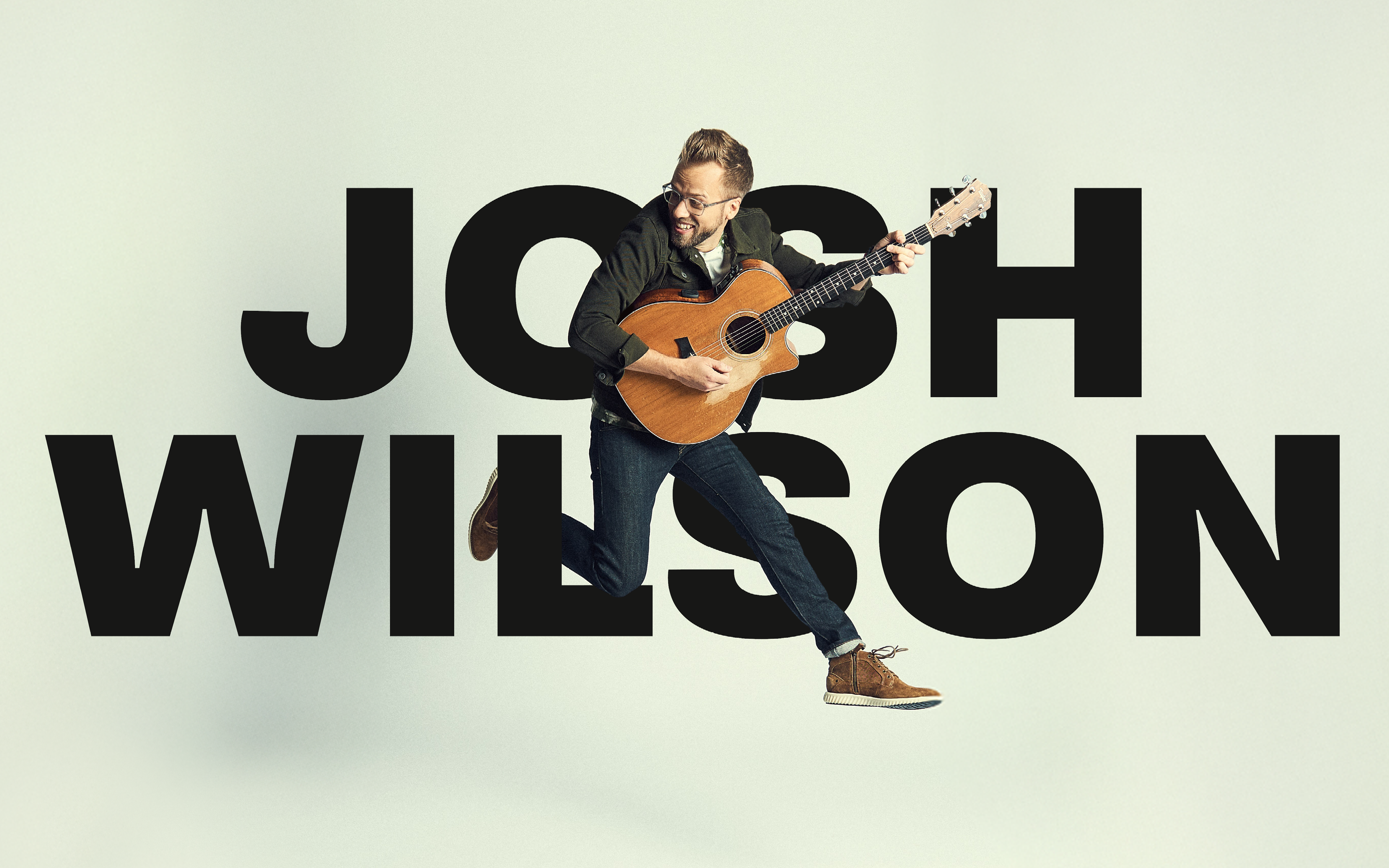Josh Wilson holding guitar and jumping in mid air in front of text "Josh Wilson".