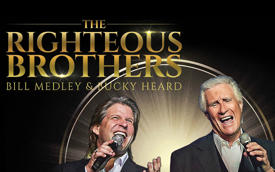 Promotional image for The Righteous Brothers’ Lovin’ Feelin’ Farewell Tour. Singers Bill Medley and Bucky Heard are shown mid-performance, each holding a microphone. The background features a glowing circular spotlight effect, with the group’s name in large gold lettering above them.